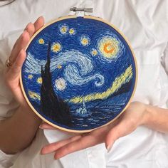 a person holding up a cross - stitch art piece with the starry night painting on it