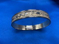 This is a vintage bangle in a gold finish from the famous Whiting & Davis Co. that started back in the late 1800's. This bangle as with most of their jewelry is made of gold-plated metal. It is truly costume jewelry but on the higher end. This type of jewelry started being made in the '50's and on.  The bangle has a a ring and feather design and it is a raised on the outside and smooth and shiny on the inside. There is a Whiting Davis in small raised metal on the inside of the bracelet as well. Formal Metal Jewelry With Etched Details, Formal Metal Etched Jewelry, Formal Etched Metal Jewelry, Gift Jewelry Bangle With Decorative Band, Vintage Metal Bangle For Ceremonial Occasion, Vintage Metal Bangle For Ceremonial Use, Victorian Silver Jewelry With Decorative Band, Antique Metal Bangle For Ceremonial Occasions, Gold Bangle With Decorative Band As Gift