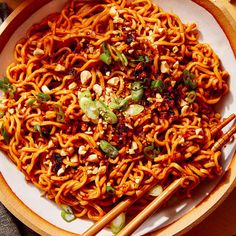 a bowl filled with noodles and chopsticks on top of a table