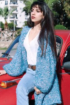 a woman sitting on top of a red car