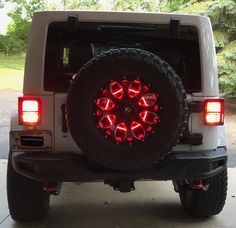 a white jeep with red lights on it's tires and tire rims is parked in a driveway