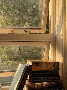 a stack of books sitting on top of a window sill