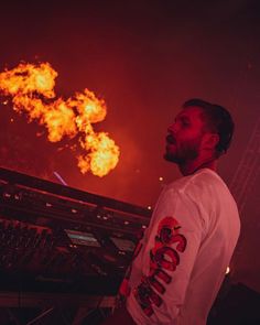 a man standing in front of a stage with fire coming out of the air behind him