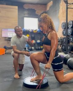 a man and woman in a gym doing squats on the ground with one leg up