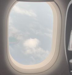 an airplane window with the view of clouds and sky from it's seat area