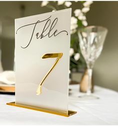 a table number is placed on top of a white table cloth with gold trimming