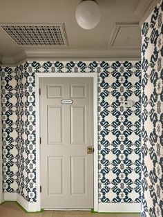 an empty room with blue and white wallpaper on the walls, door to another room