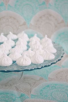 there are many small pieces of meringue on the glass platter with blue and white wallpaper