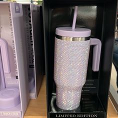 a purple cup with a straw in it sitting on top of a shelf next to other items