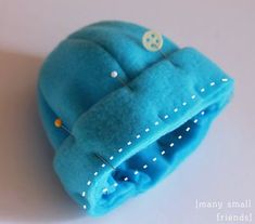 a blue hat with buttons on it sitting on top of a white table next to a pair of scissors