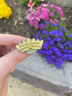 someone holding up a pin with flowers in the background