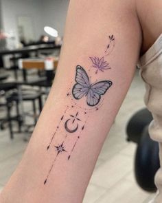 a woman's arm with a butterfly and stars tattoo on the back of her left arm