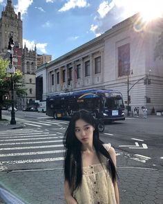 a woman standing in front of a bus on a city street