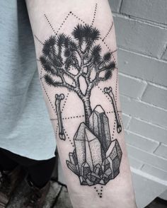 a man's arm with a tree and rocks tattoo on the left inner forearm