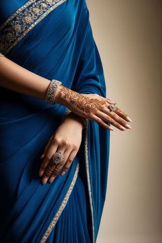 a woman in a blue sari with henna on her hand and bracelets