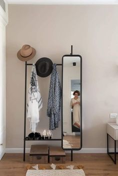 a woman is taking a selfie in the mirror while standing next to a coat rack