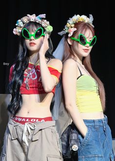 two young women with green sunglasses and flower crowns on their heads are standing next to each other