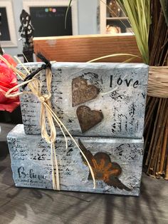 two wooden hearts tied with twine on top of each other in front of flowers