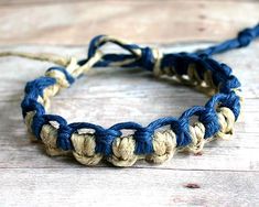 a close up of a bracelet on a wooden surface with blue and white braiding