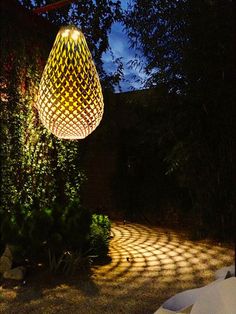 an outdoor lighting fixture in the middle of a garden at night with shadows on the ground