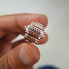 a person is holding a ring made out of three different colored stone blocks in their left hand