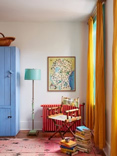 a room with a blue cabinet, yellow curtains and a red chair in front of it