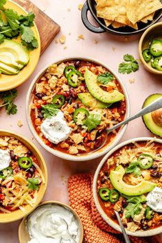 bowls of mexican soup with tortilla chips and avocado on the side