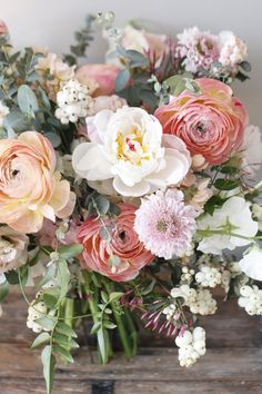 a vase filled with pink and white flowers on top of a wooden table next to a wall