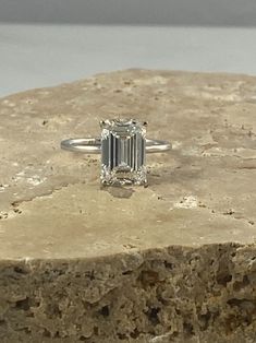 an emerald - cut diamond sits atop a rock