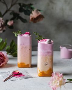 two vases with pink and yellow flowers on the table next to each other, one is filled with liquid