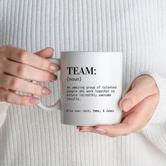 a woman is holding a coffee mug with the words team on it in both hands