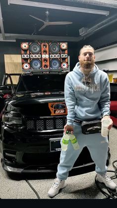 a man standing in front of a car with speakers on it's headphones