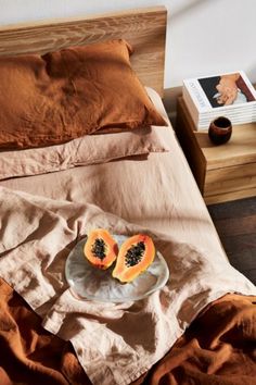 a plate with two pieces of fruit on it sitting on a bed next to an open book