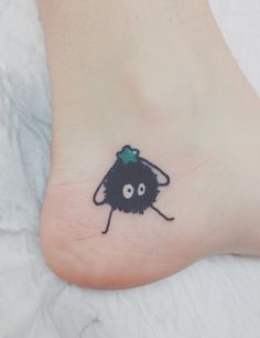 a small black cat with a green bow on it's head is shown on the foot