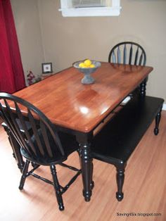 a wooden table with chairs around it and a bowl of fruit sitting on top of the table