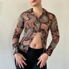 "This is an early 2000s blouse with paisley print, metallic detail, and crinkle effect fabric. Wear it buttoned, open, tucked, or tied. \"No boundaries\" label tag Fits Medium / Large Bust 37\" Waist 32\" Sleeve 24\" Length 23\" Polyester Great condition" Trendy Cheap Tops With Paisley Print, Cheap Fitted Blouse With Paisley Print, Cheap Patterned Shirt With Paisley Print, Cheap Paisley Print Patterned Shirt, Cheap Long Sleeve Tops With Paisley Print, Cheap Long Sleeve Top With Paisley Print, Cheap Paisley Print Patterned Blouse, Luxury Paisley Print Top With Spread Collar, 2000s Blouse