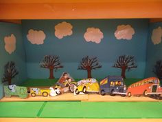 a group of toy cars sitting on top of a green floor next to trees and clouds