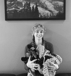 black and white photograph of a woman holding two crocheted teddy bears in front of a mountain scene