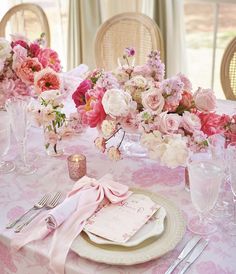 the table is set with pink and white flowers in vases, napkins, and silverware