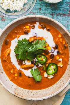 a white bowl filled with soup and garnished with cilantro, sour cream and green peppers