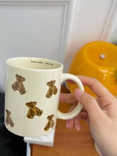 a hand holding a coffee mug with brown teddy bears on the front and back of it