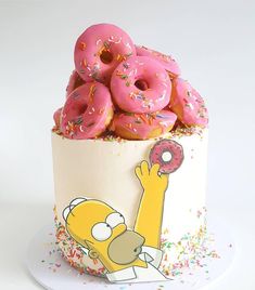 a cake with pink frosting and sprinkles on it, topped with donuts