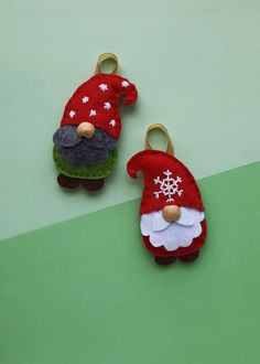 two small christmas gnomes are sitting on a green surface