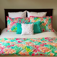 a bed with colorful pillows on top of it and a white pillow in the middle