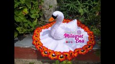 a swan made out of flowers is sitting in front of some bushes and plants,