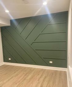 an empty room with wood floors and green painted panels on the wall, in front of a ceiling fan