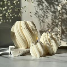 two white candles sitting next to each other on a table