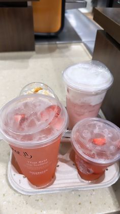 three plastic cups filled with drinks sitting on top of a counter