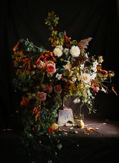 a vase filled with lots of flowers sitting on top of a black table next to a piece of cake