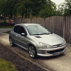 a silver car parked in front of a wooden fence